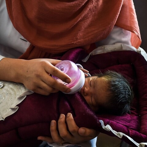 A nurse feeds a newborn baby rescued and brought to Ataturk Children hospital, after the mother was killed during a gunmen attack on a maternity hospital, in Kabul on May 15, 2020.