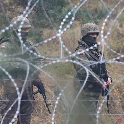 Polish servicemen behind a barbed wire fence at the Belarus-Polish border in the Grodno region, Belarus, 10 November 2021.