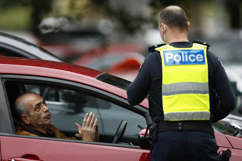 Police check identification of drivers outside public housing towers on Racecourse Road in Flemington, Melbourne, Sunday, July 5, 2020.