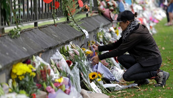 A woman pauses as she lays flowers on a wall at the Botanical Gardens in central Christchurch (File Photo).