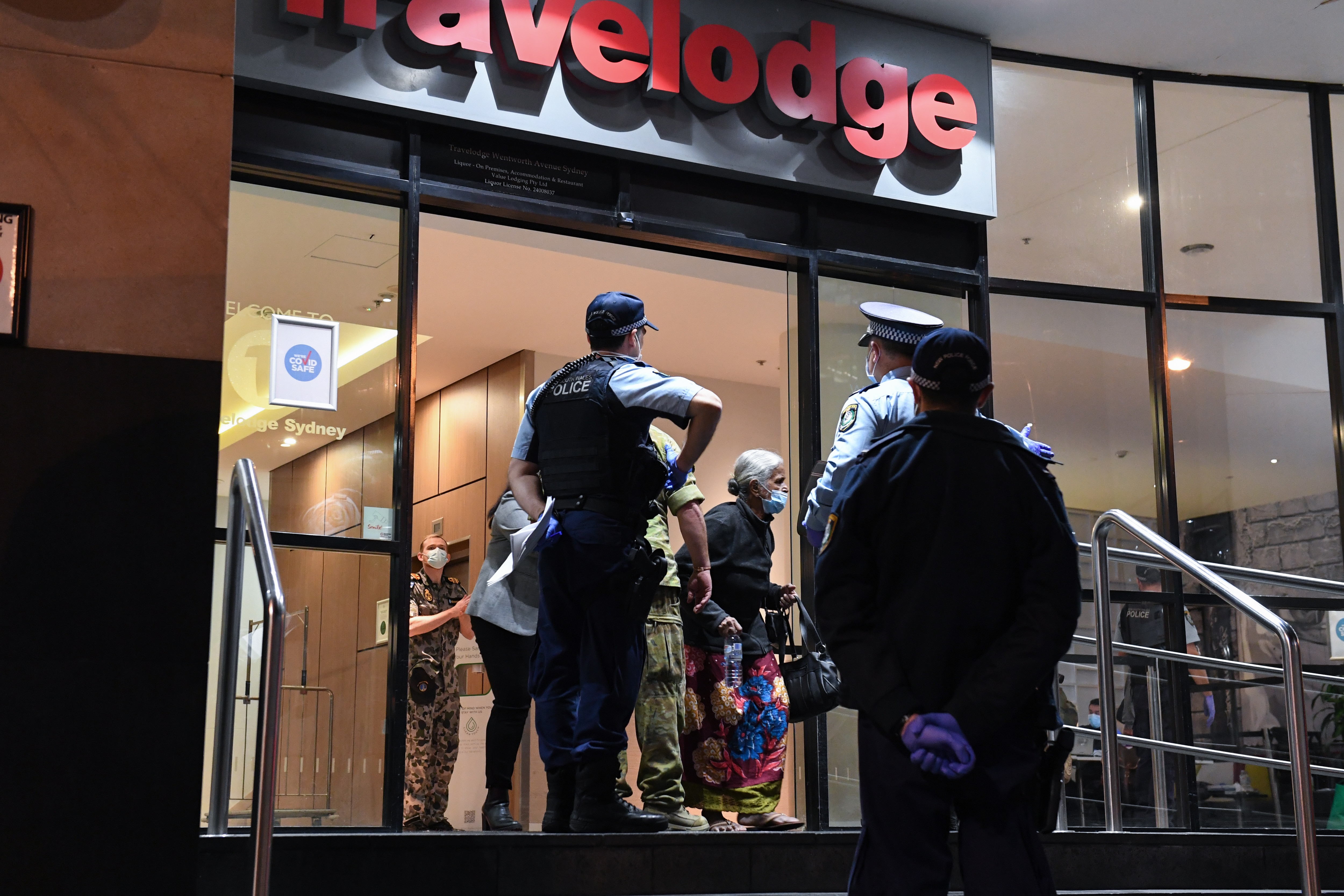 Guests departing Sydney's Travelodge under police guard on 25 August, 2020.