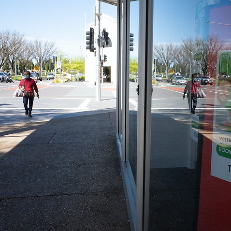 A resident walks past a pharmacy offering COVID-19 vaccination in Canberra, Wednesday, October 6, 2021