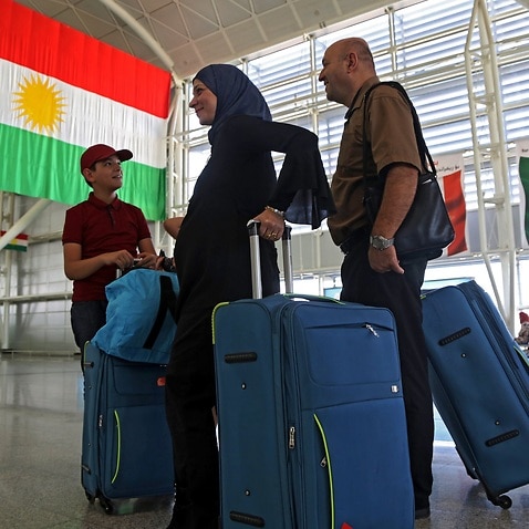 Passengers queue at a check-in counter prior the flight ban at Erbil International Airport.
