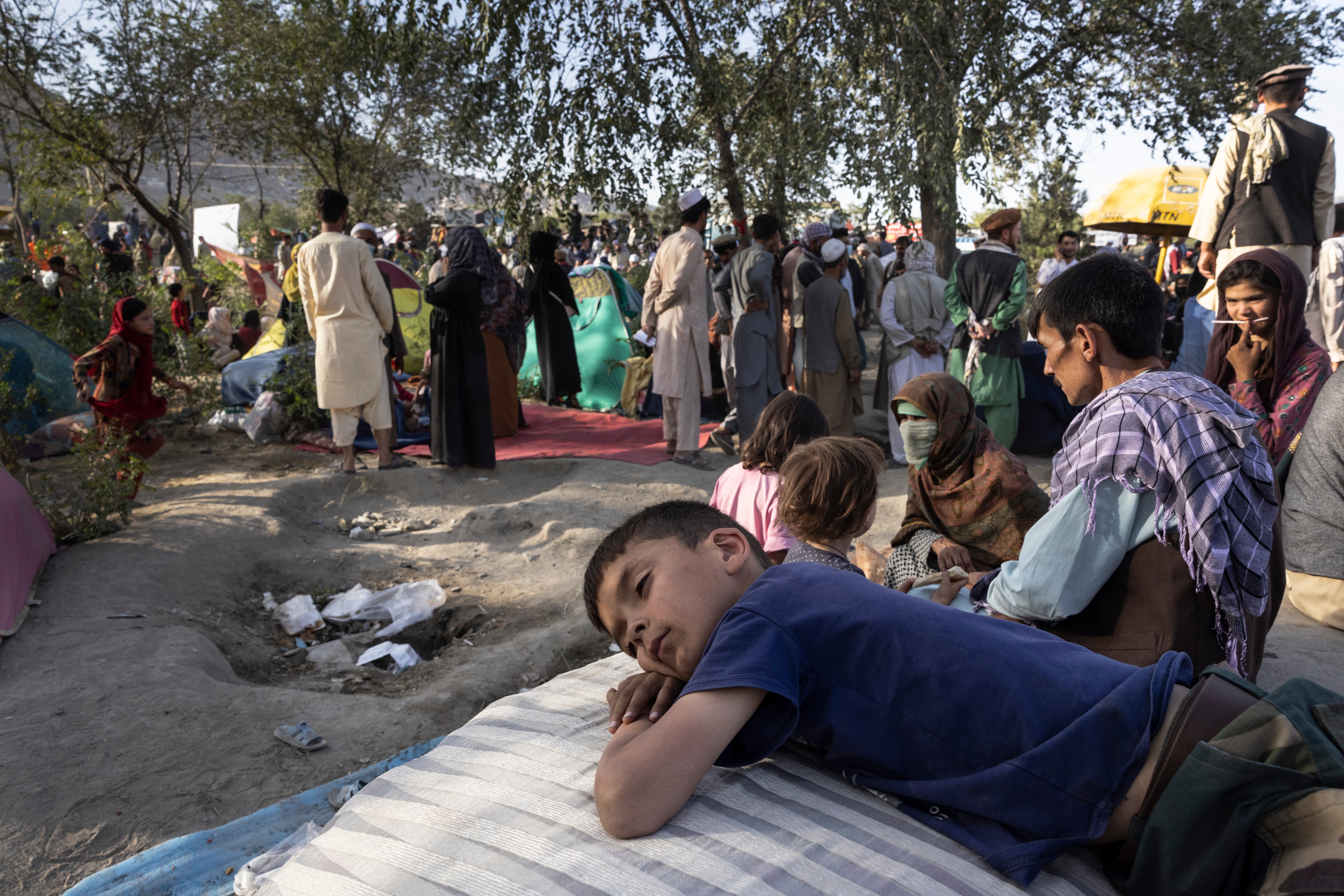 Displaced Afghans rest after they arrive at a makeshift camp from the northern provinces on 10 August, 2021 in Kabul, Afghanistan.