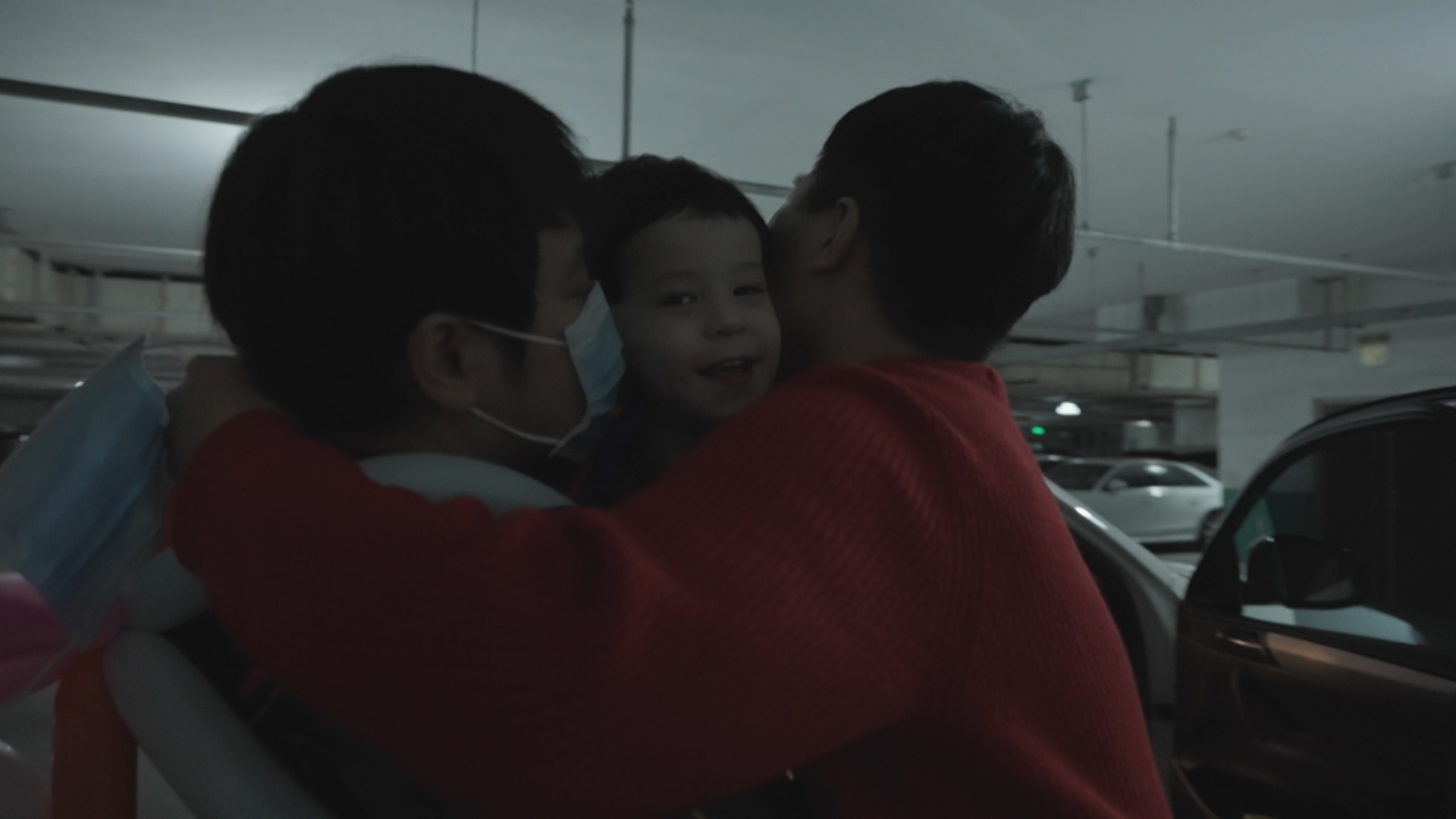 Chinese male couple hug their surrogate son