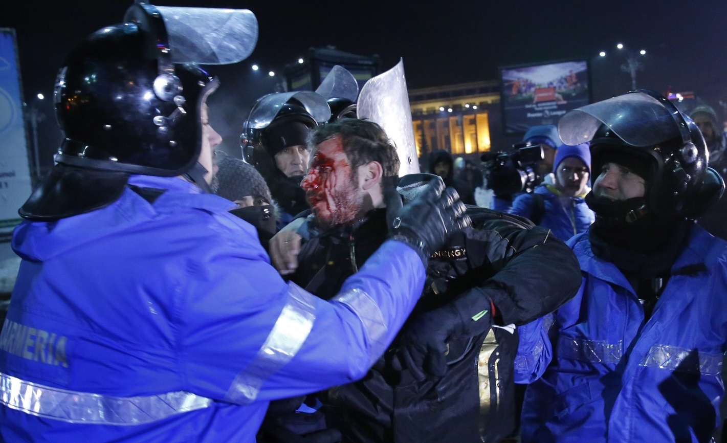 A wounded young man is arrested by the riot police during a protest rally in front of government headquarters in Bucharest (AAP) A wounded young man is arrested by the riot police during a protest rally in front of government headquarters in Bucharest (AAP)