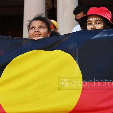 Gözaltında ölümleri protesto için Sydney yapılan yürüyüşte, Town Hall önünde Aborijin bayrağını tutan çocuklar.