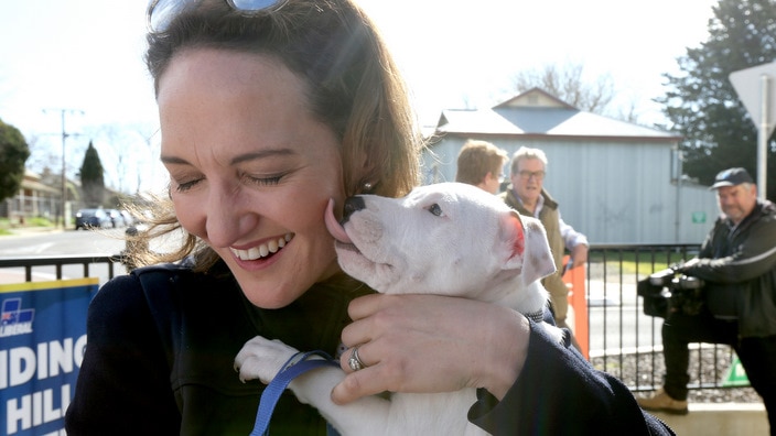 Liberal candidate Georgina Downer gets a kiss from a puppy at a Mayo by-election pre-polling booth in Mount Barker.