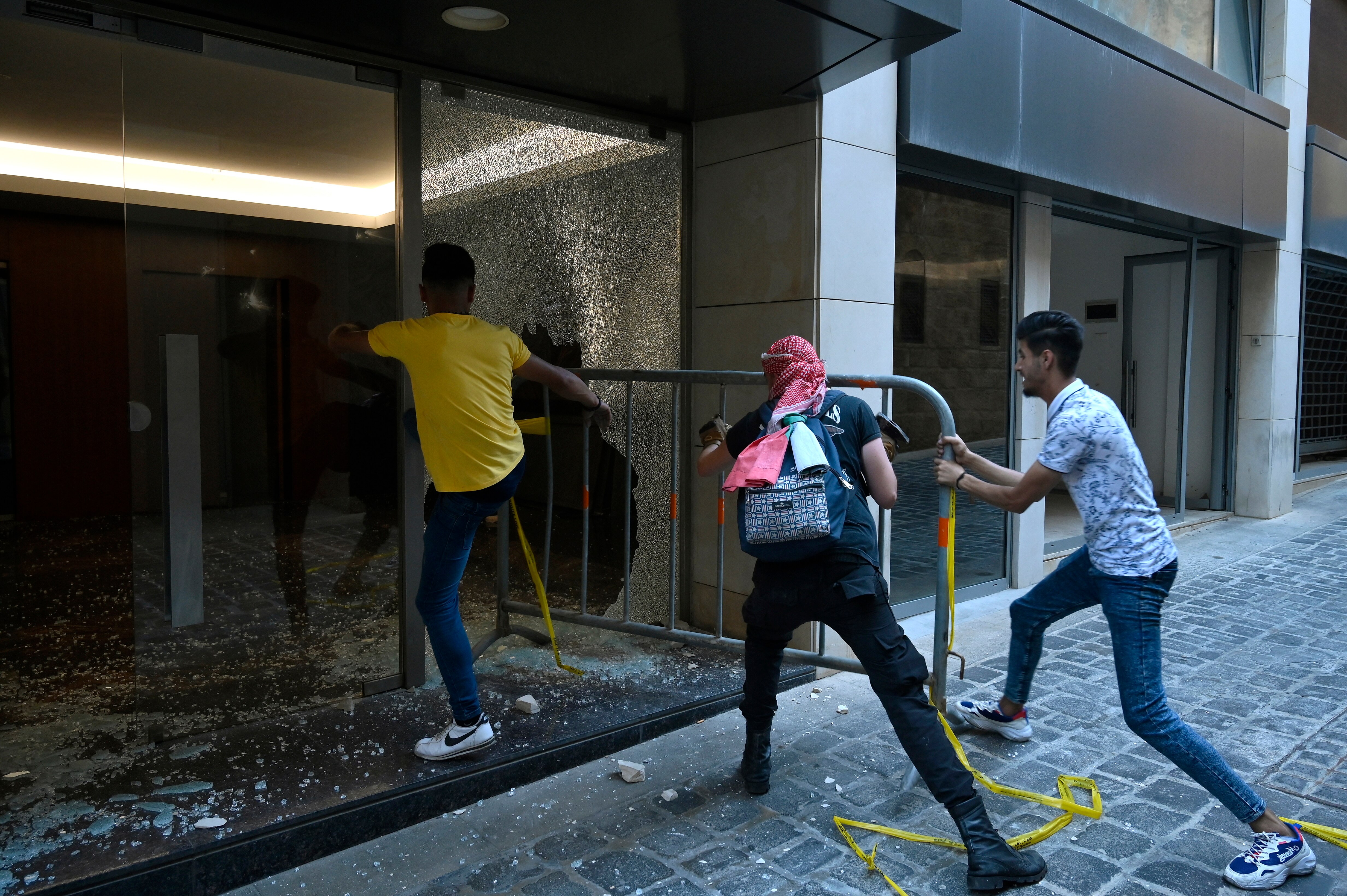 nti-government protesters using a metal barrier to smash glass panels