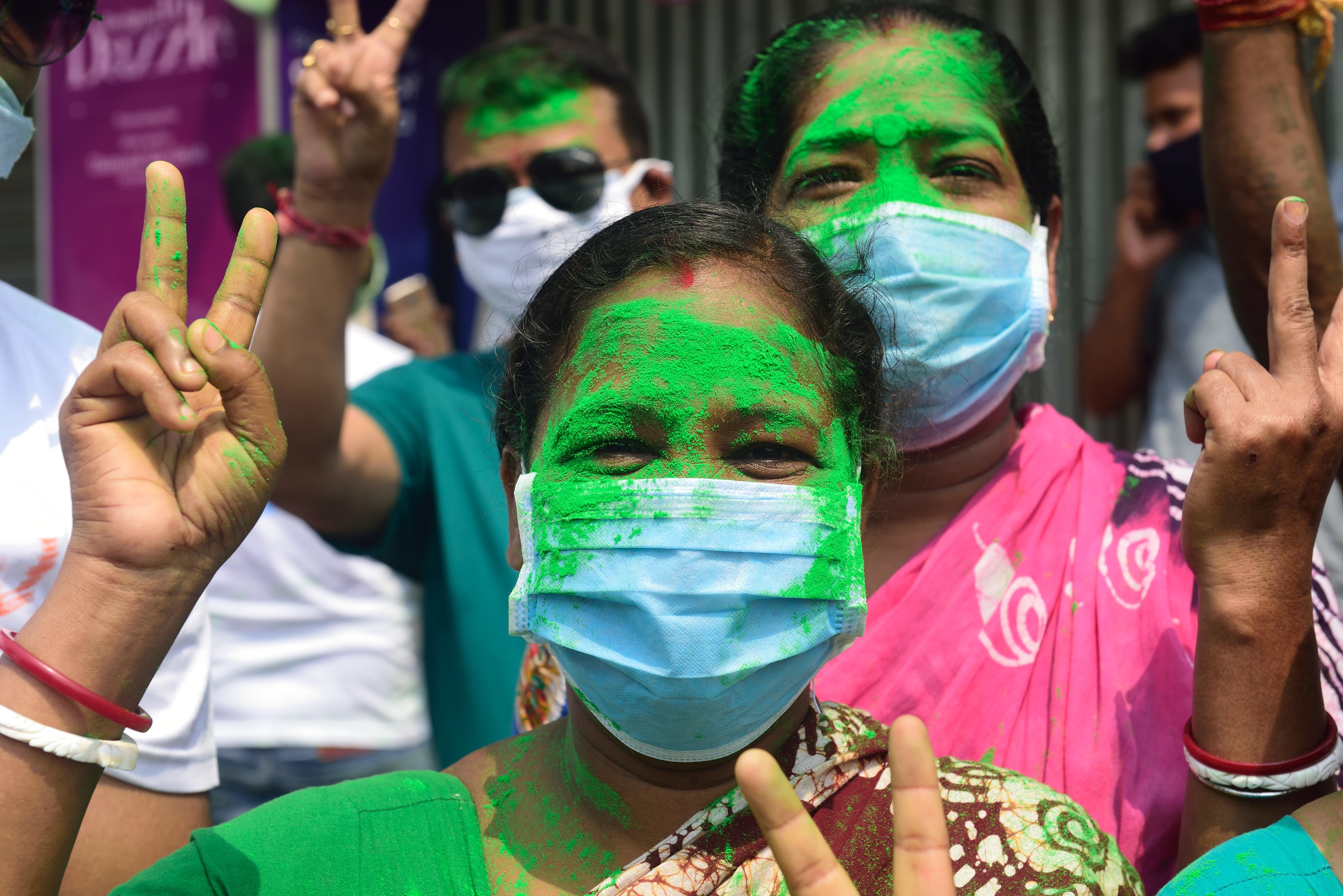 A Trinamul Congress supporter wearing a mask makes a victory sign to celebrate TMC's victory in the West Bengal Election, 2 May, 2021.