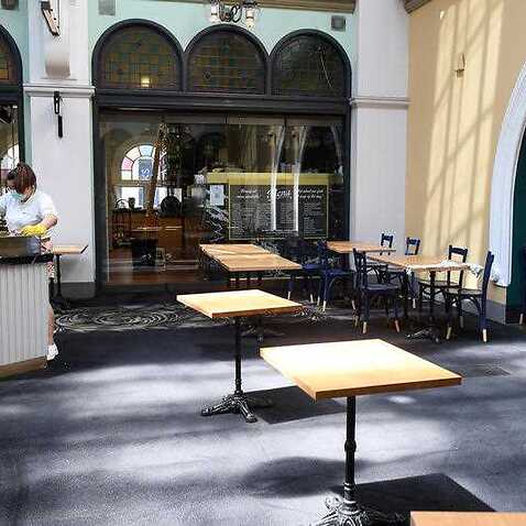 Staff prepare empty cafe seating areas for reopening, at the QVB in Sydney, Saturday, 9 October, 2021.