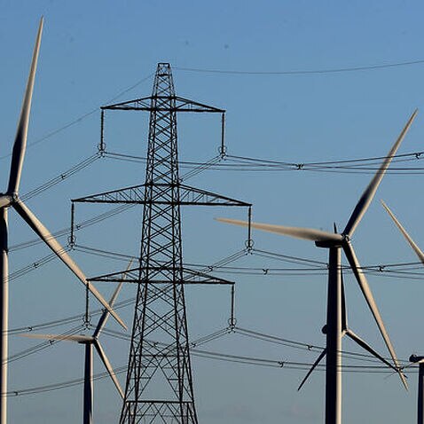 A wind farm amongst electricity pylons 