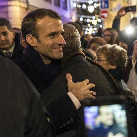 French President Emmanuel Macron (2-L) hugs a visitor to the Christmas market, as he visits the terror attack scene, in Strasbourg.