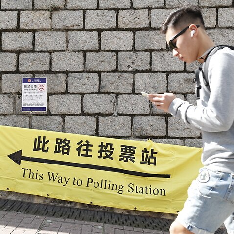 A person walks past a banner showing the way to a polling station for the 2019 District Council Ordinary Election in Hong Kong.