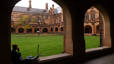 A student sits next to the quadrangle at the University of Sydney,
