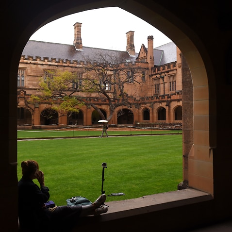A student sits next to the quadrangle at the University of Sydney, 