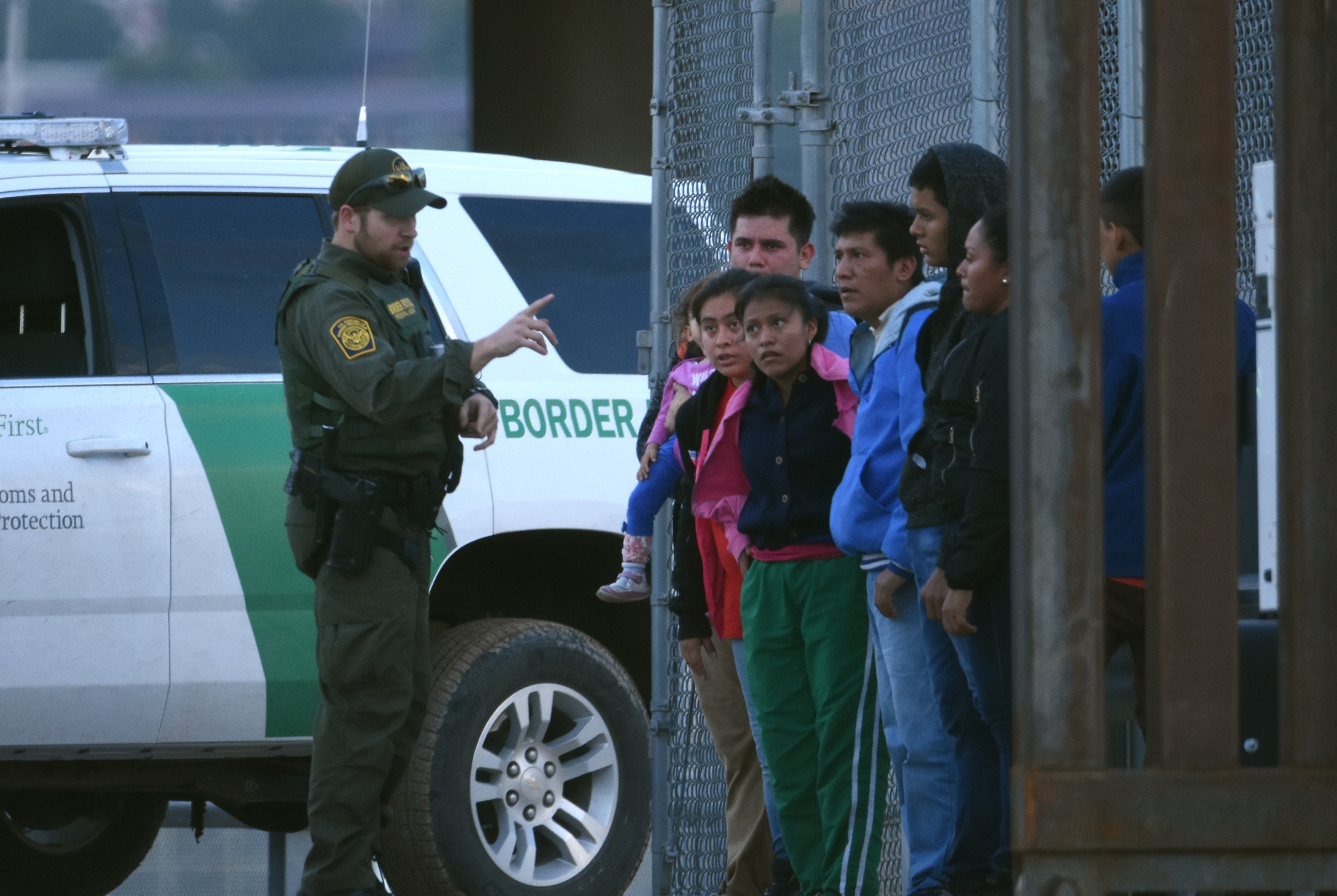 An agent of the US Border Forces talks to a group of group of young Central American migrants.