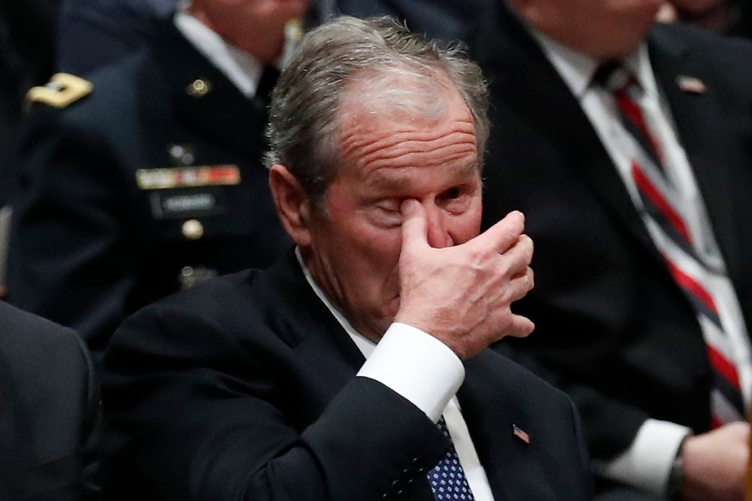 Former President George W Bush wipes his eye at the State Funeral for his father.