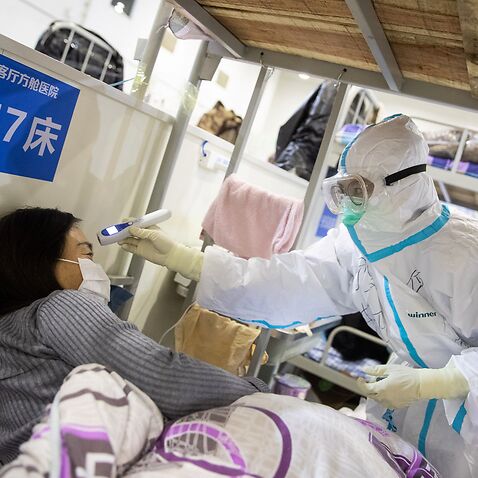 A medic working inside a makeshift hospital in Wuhan, China, checks the temperature of a patient in April, 2020.