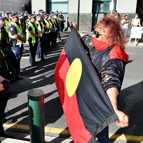 Police and a Black Lives Matter protestor are seen during a protest outside the Roma Street Magistrates Court in Brisbane.