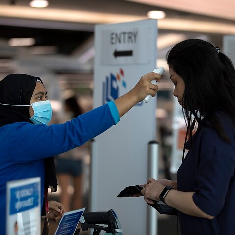 A staff takes the temperature of a visitor at the entrance of a library in Singapore.