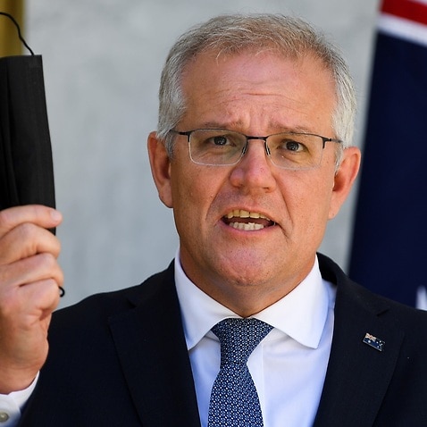 Australian Prime Minister Scott Morrison holds up a face mask as he speaks during a press conference