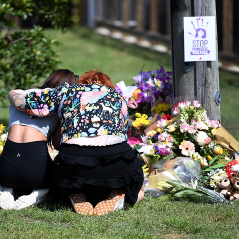 Mourners hug at a makeshift shrine near the scene of the car fire that killed Hannah Clarke and her three children