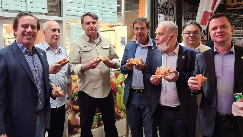 Brazil President Jair Bolsonaro (third from left) eating pizza on the sidewalk in New York City.