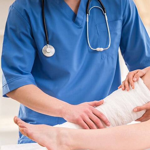 Image of a nurse tending to a cast on a person's leg