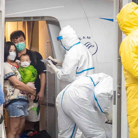 People disembark a chartered Xiamen Airline plane, arrive at Wuhan Tianhe International Airport in Wuhan to be met by medical officials.