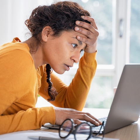 Young woman feeling stressed while looking at computer