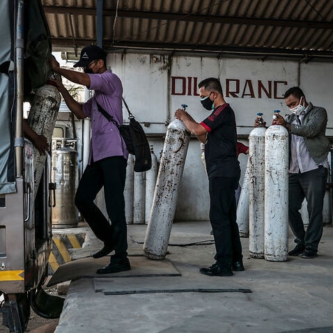 Workers load oxygen tanks for hospitals into a truck at an oxygen distribution facility on 7 July, 2021 in Yogyakarta, Indonesia.
