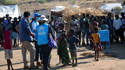Members of the United Nations High Commissioner for Refugees (UNHCR) monitor the distribution of food rations at Um Rakuba refugee camp.