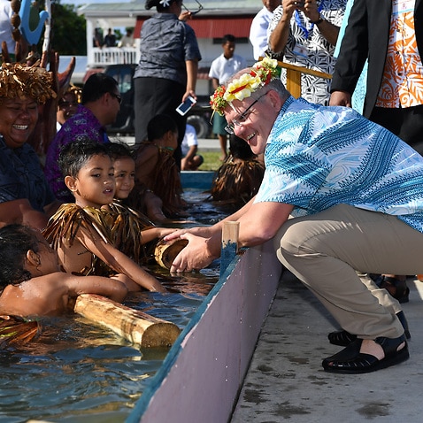 Children symbollically represent climate change greet Prime Minister Scott Morrison as he arrives for the Pacific Islands Forum in Funafuti, Tuvalu.