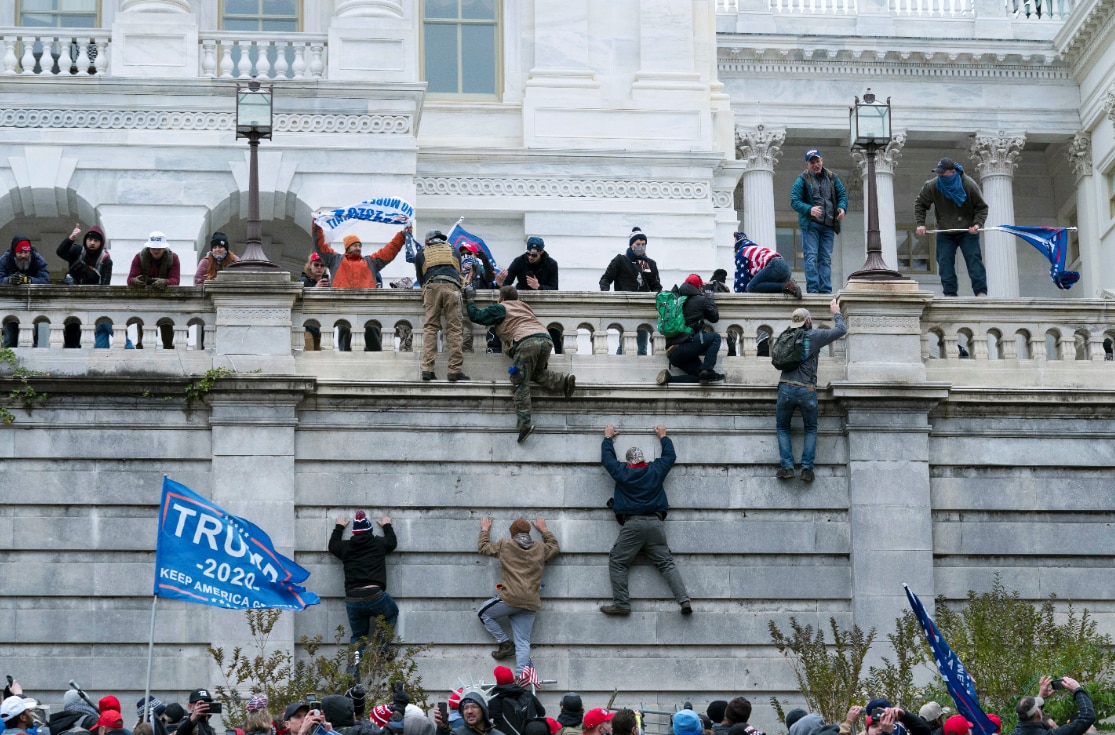 Supporters of former Preisdent Donald Trump climbing the west wall of the US Capitol in Washington during the 6 January riot.