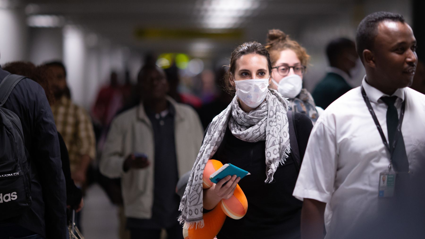 A passenger wears a mask arriving at an airport