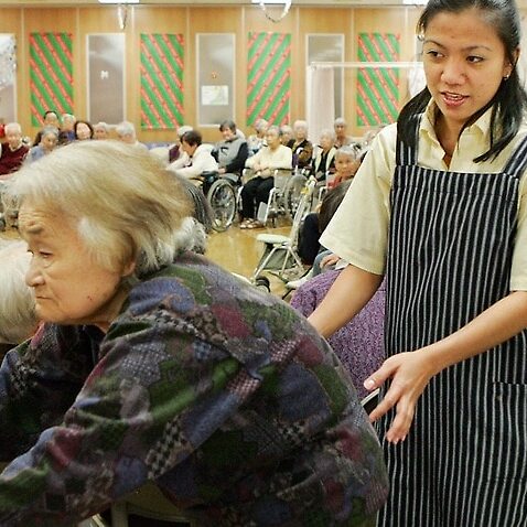 Maria Falqueza, 25, from Manilla, supports a Japanese elderly woman prior to a year-end party in a care support facility in Mizuho, suburban Tokyo, 25 DEC 2006
