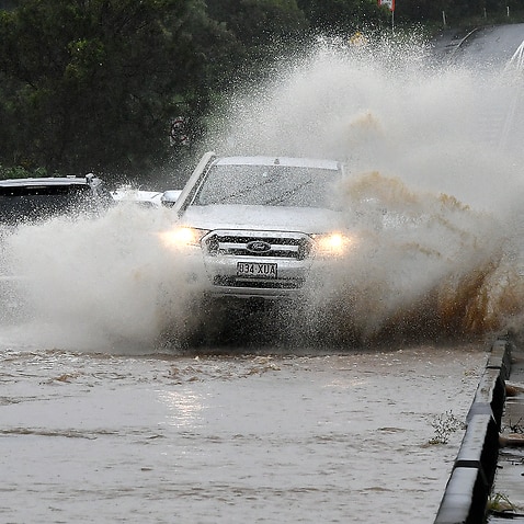 Vehicles travel over a flooded causeway on the Gold Coast on Monday.