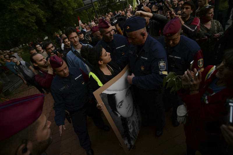 A counter-protester holding a banner faces a police officer as the Hungarian far-right party Mi Hazank Mozgalom rally. 