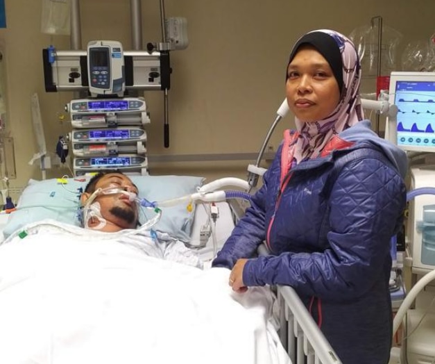 Rahimi Ahmad recovering in hospital with his wife, Nor Azila Abd Wahid, by his side.