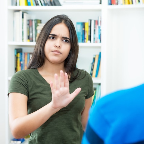 Hispanic female young adult gesturing stop and social distancing