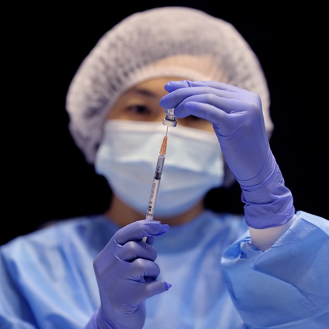 A health care worker fills a syringe with the Pfizer vaccine.