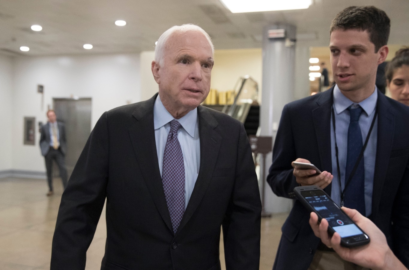 Republican Senator from Arizona John McCain (L) is followed by members of the news media duirng Republican attempts to repeal Obamacare