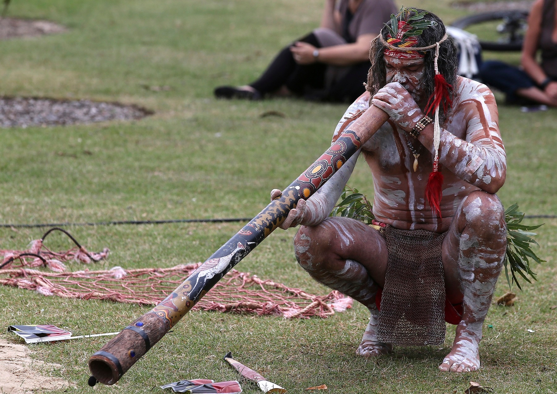 A man plays a didgeridoo at an Australia Day event.  