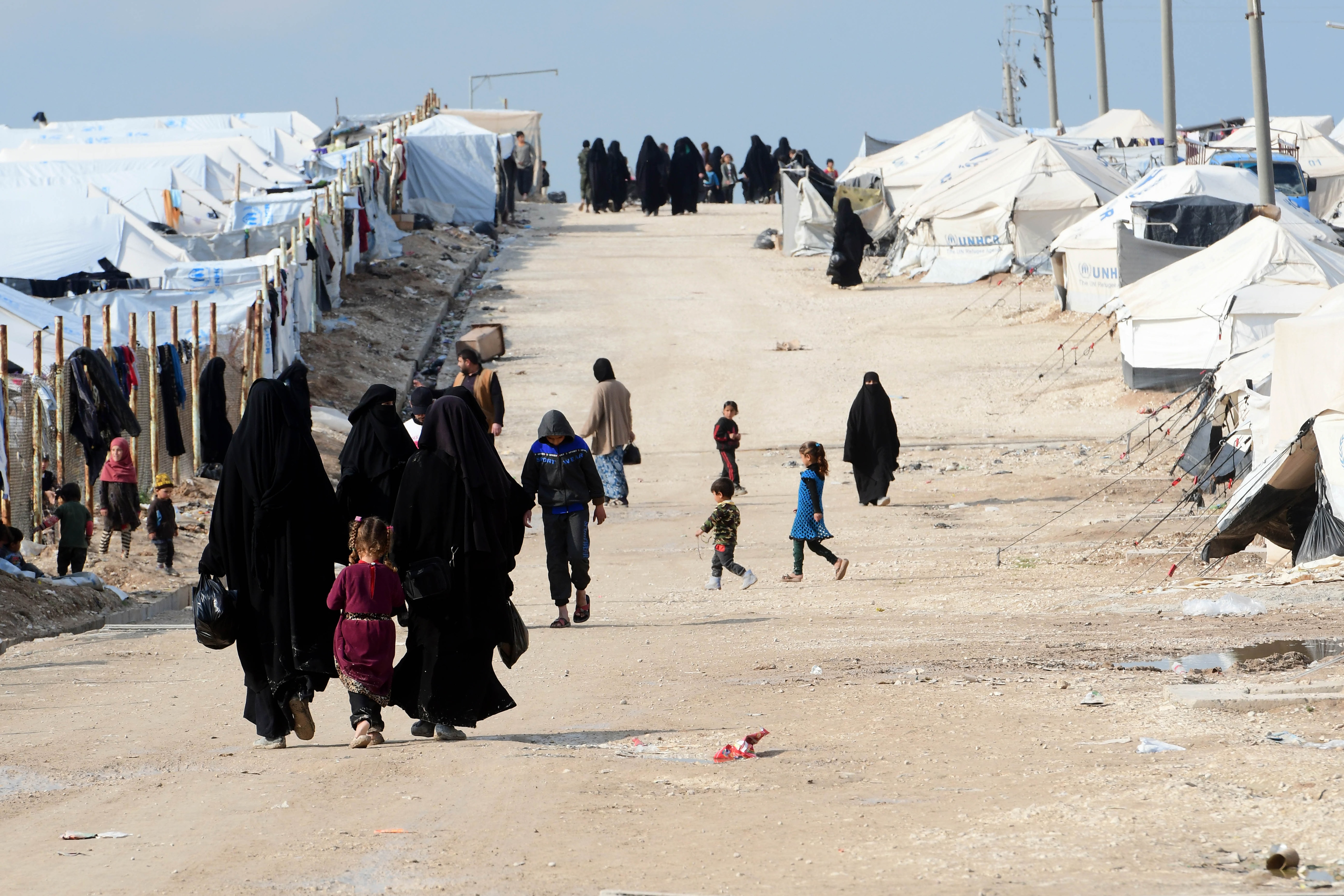 Women and children walk inside the camp.