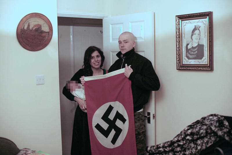 Adam Thomas et sa partenaire Claudia Patatas avec leur nouveau-né devant un drapeau nazi. Le couple a nommé leur enfant après Adolf Hitler.