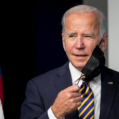 .S. President Joe Biden removes his face mask as he arrives to speak in the South Court Auditorium on the White House campus October 14, 2021 in Washington.