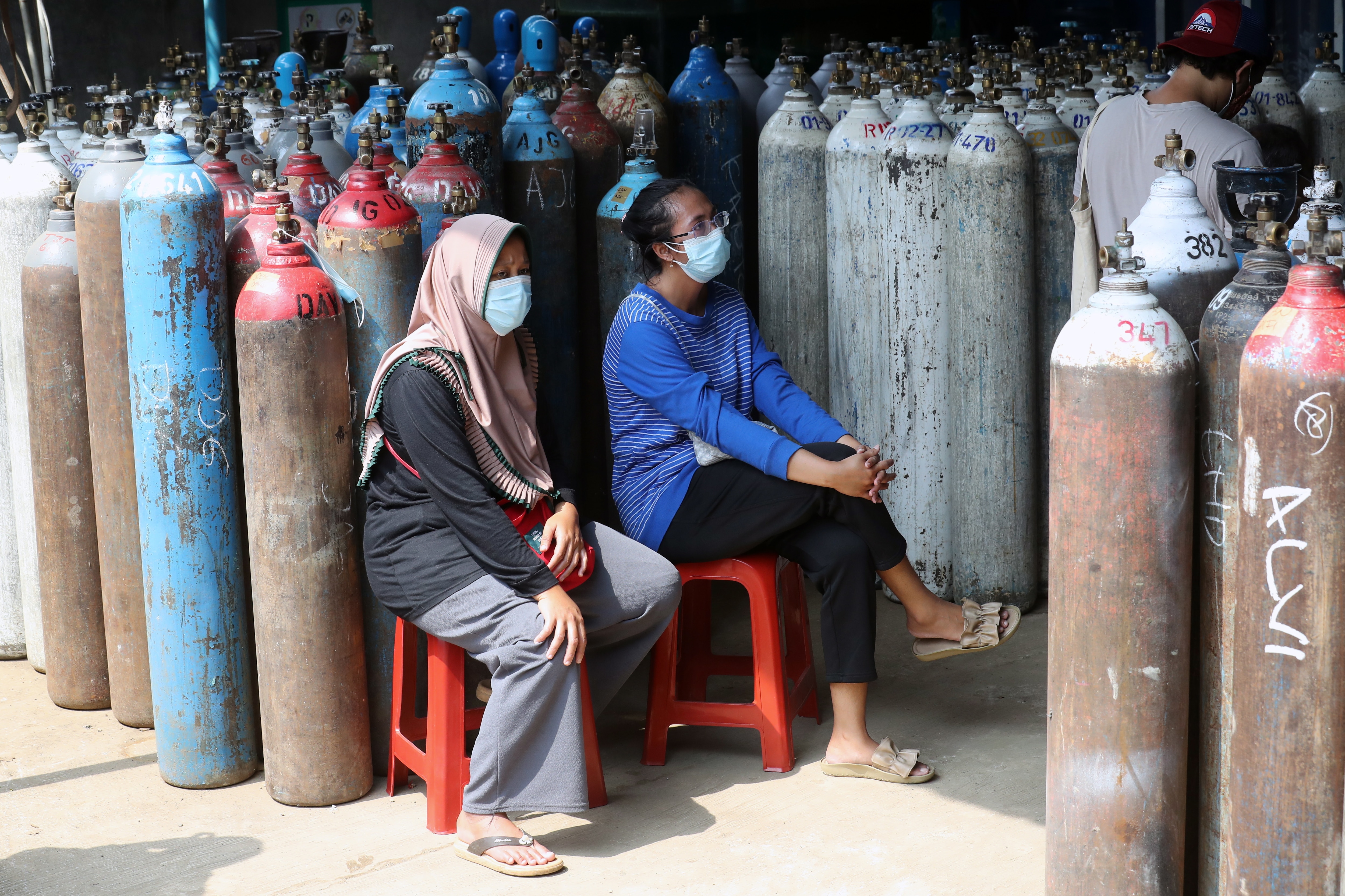 Two Indonesian women wait in the line for oxygen at an oxygen refill station in Bogor, Indonesia.