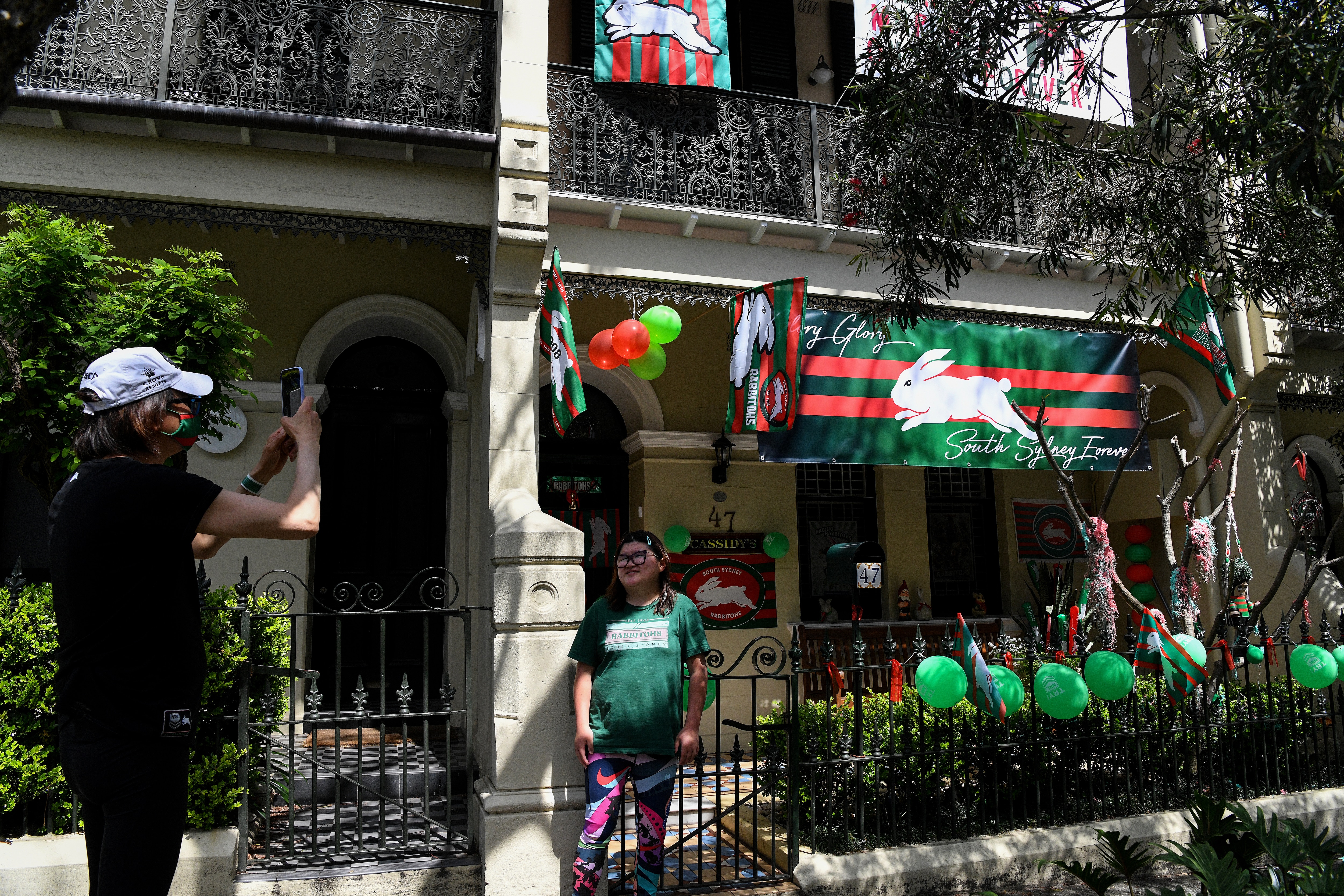 Fans take a photos in front of a home covered in South Sydney Rabbitohs signage in the suburb of Waterloo