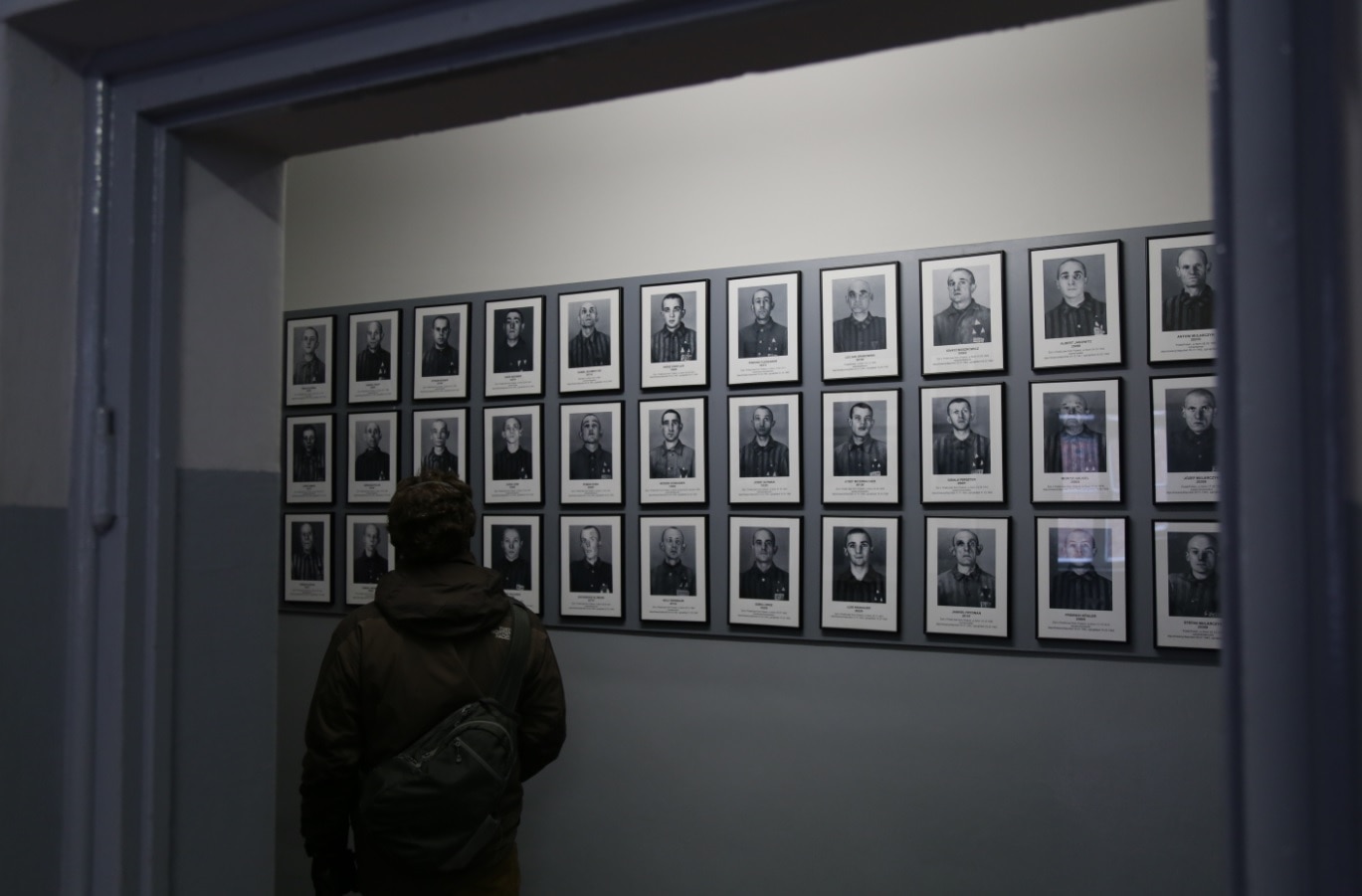 A visitor examining one of the many portraits of murdered prisoners, which line the corridor of Block Six at Auschwitz I A visitor examining one of the many portraits of murdered prisoners, which line the corridor of Block Six at Auschwitz I